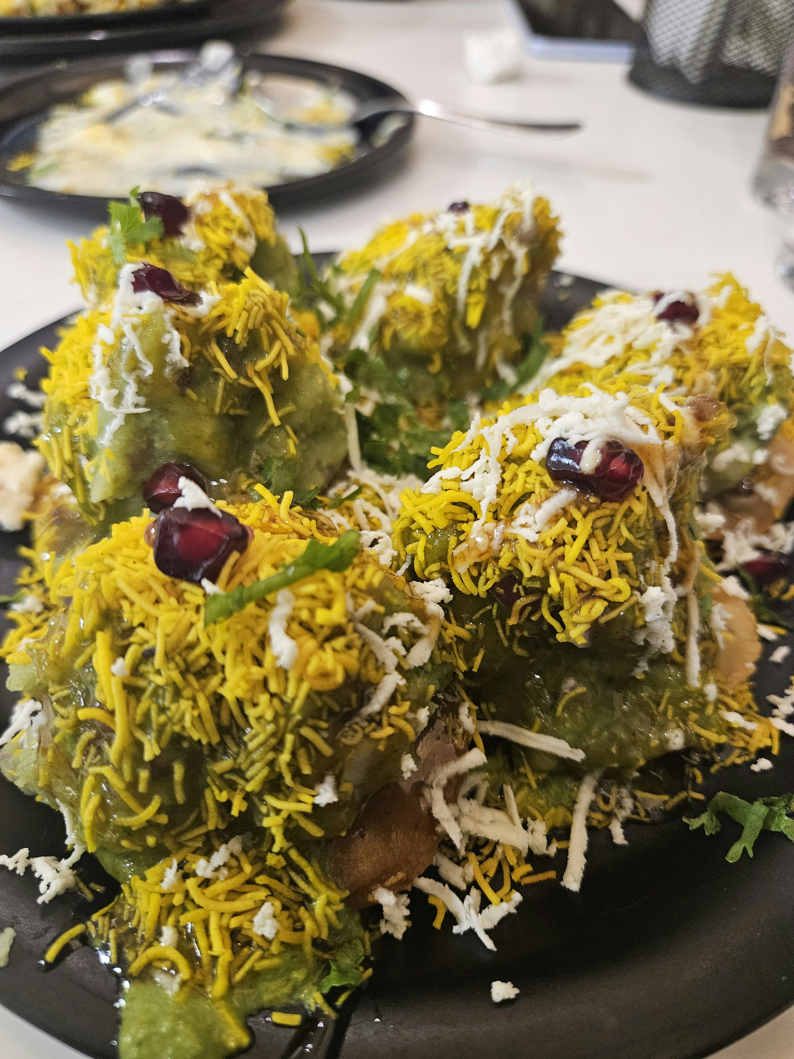 Colorful papdi chaat with crispy papdi, yogurt, green and tamarind chutneys, sev and pomegranate seeds