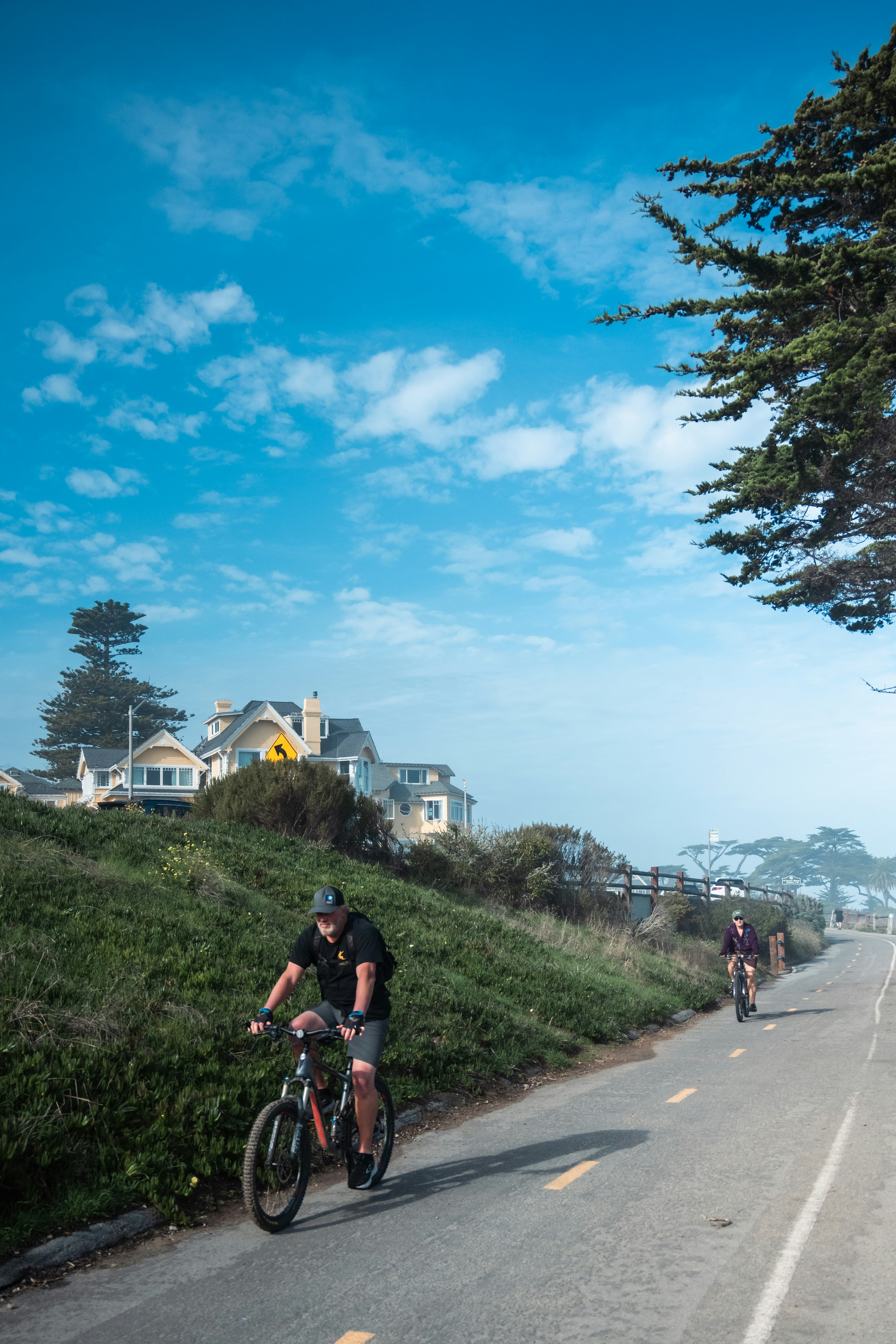 A couple of people riding bikes down a road photo – Free Man Image on ...