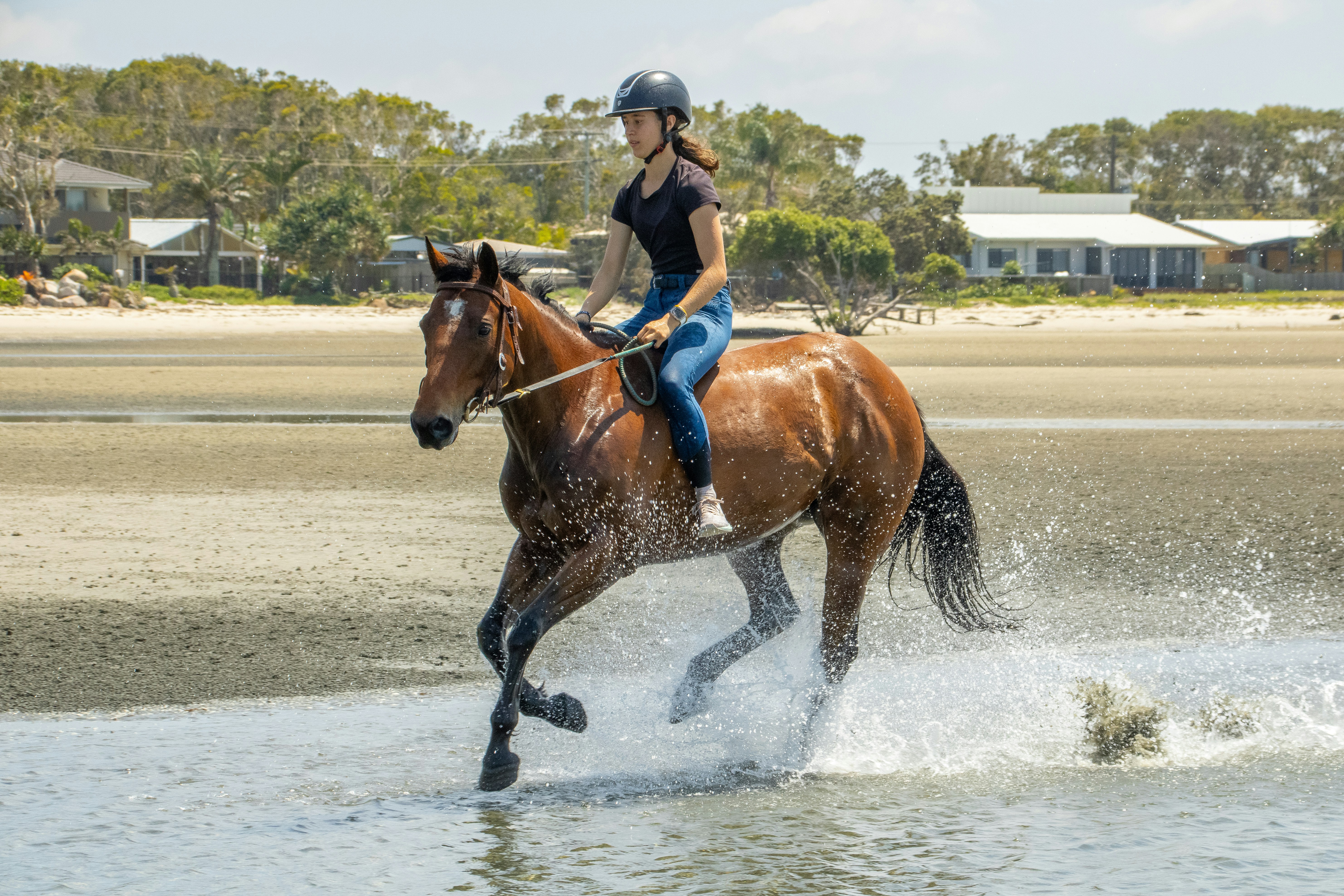 A woman riding a horse across a body of water