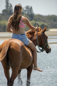A woman riding on the back of a brown horse