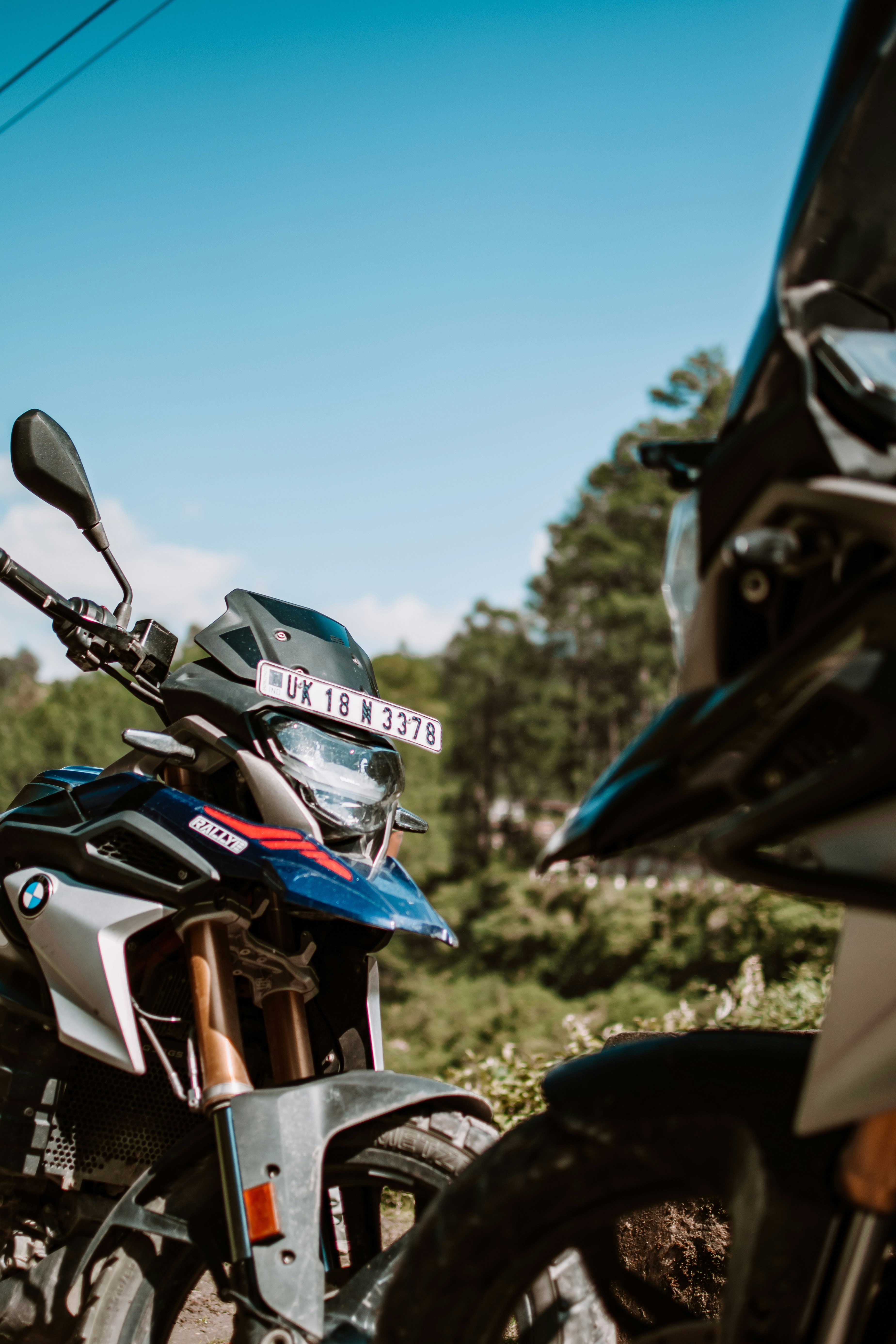 Two motorcycles parked next to each other on a dirt road