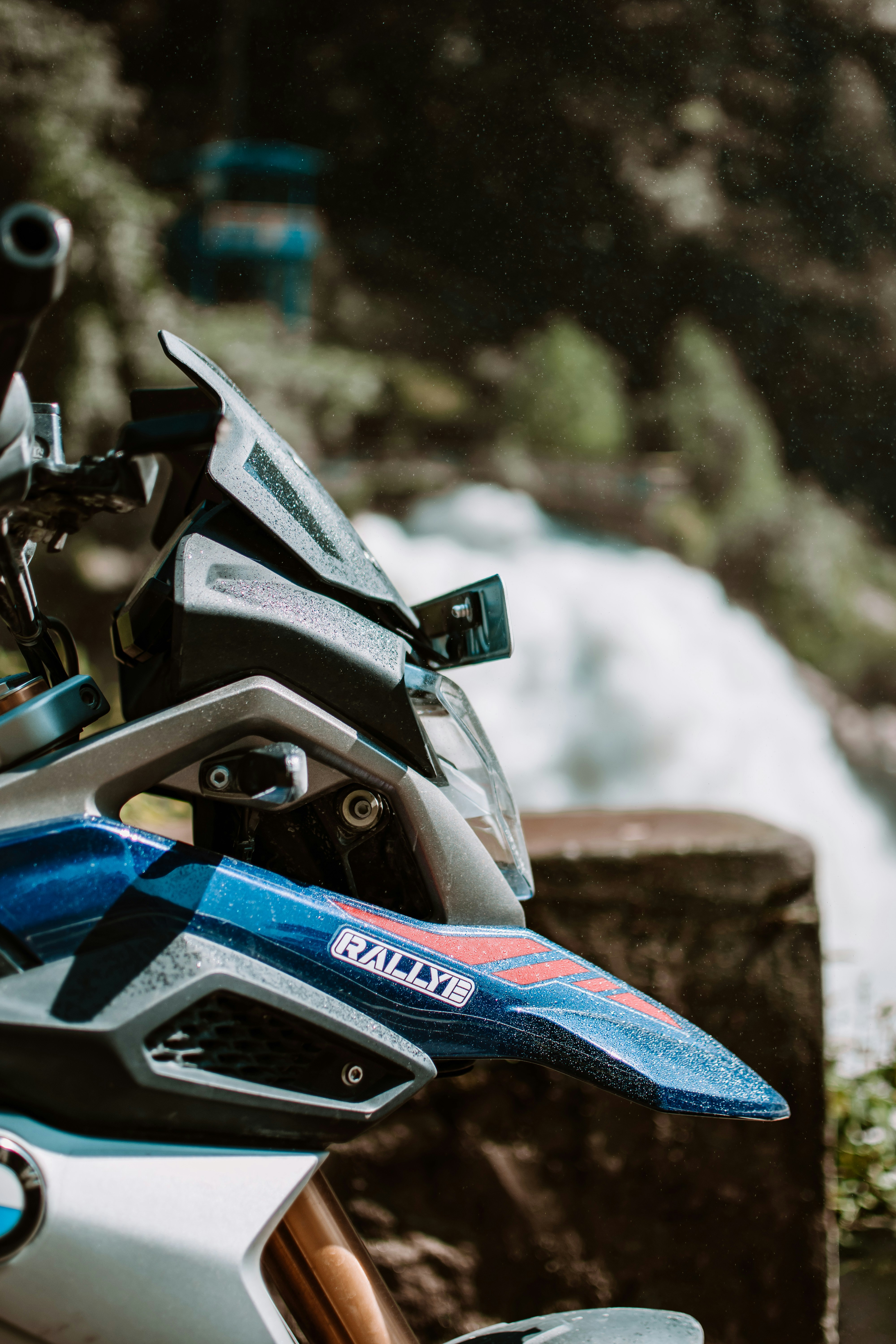 A motorcycle parked next to a river with a waterfall in the background