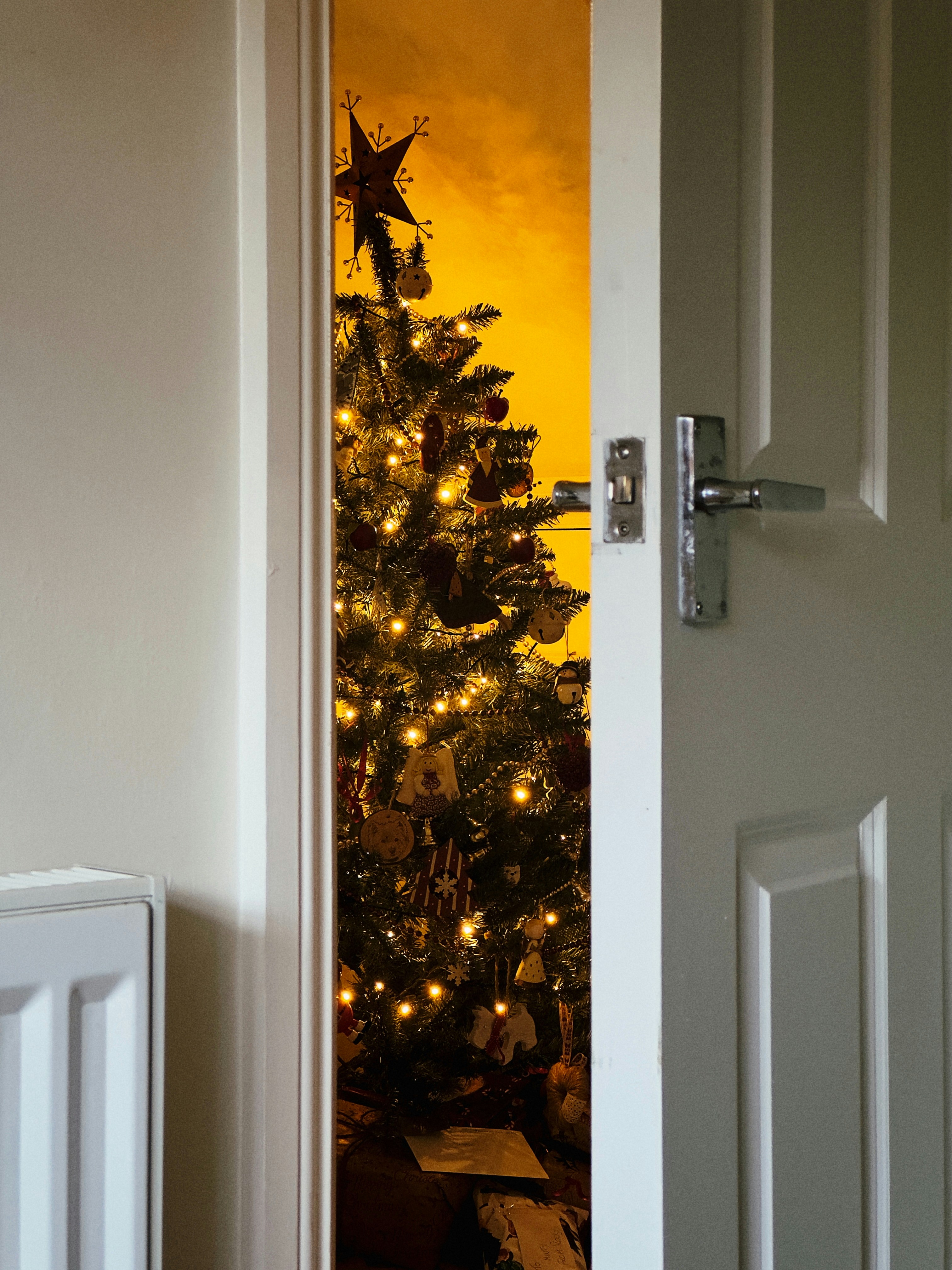Un árbol de Navidad se ve a través de una puerta abierta
