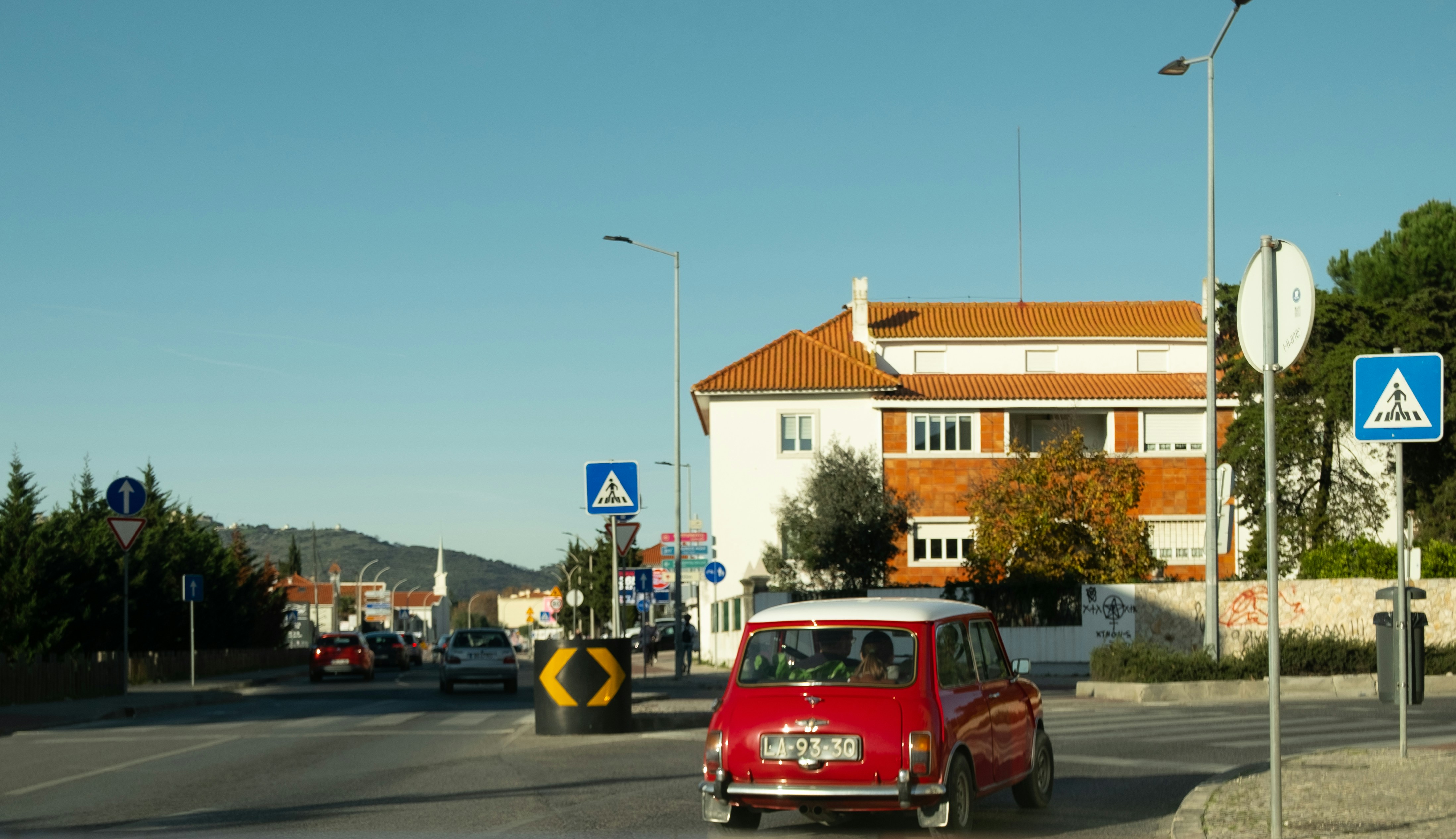 A small red car driving down a street