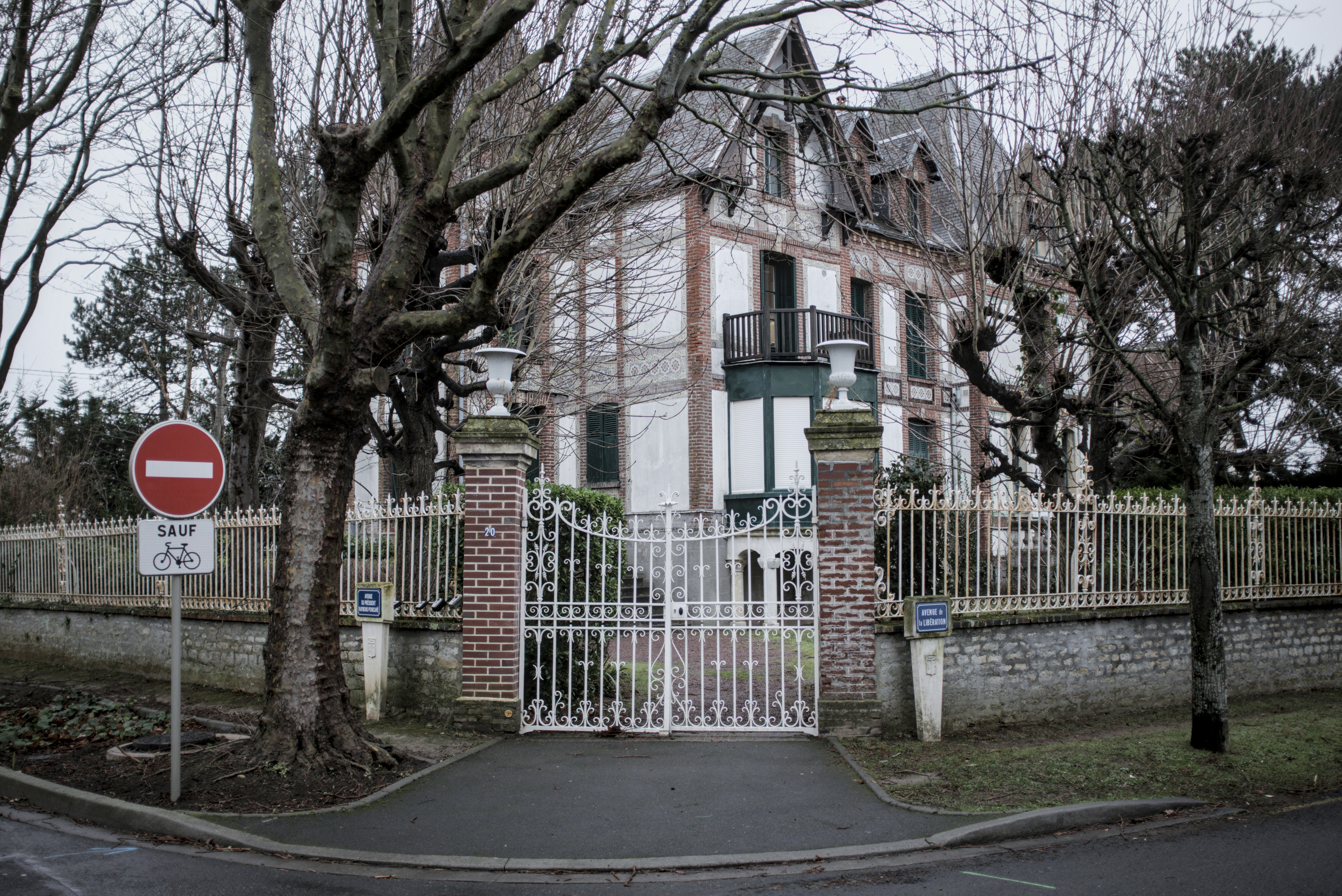A house with a gate and a stop sign in front of it
