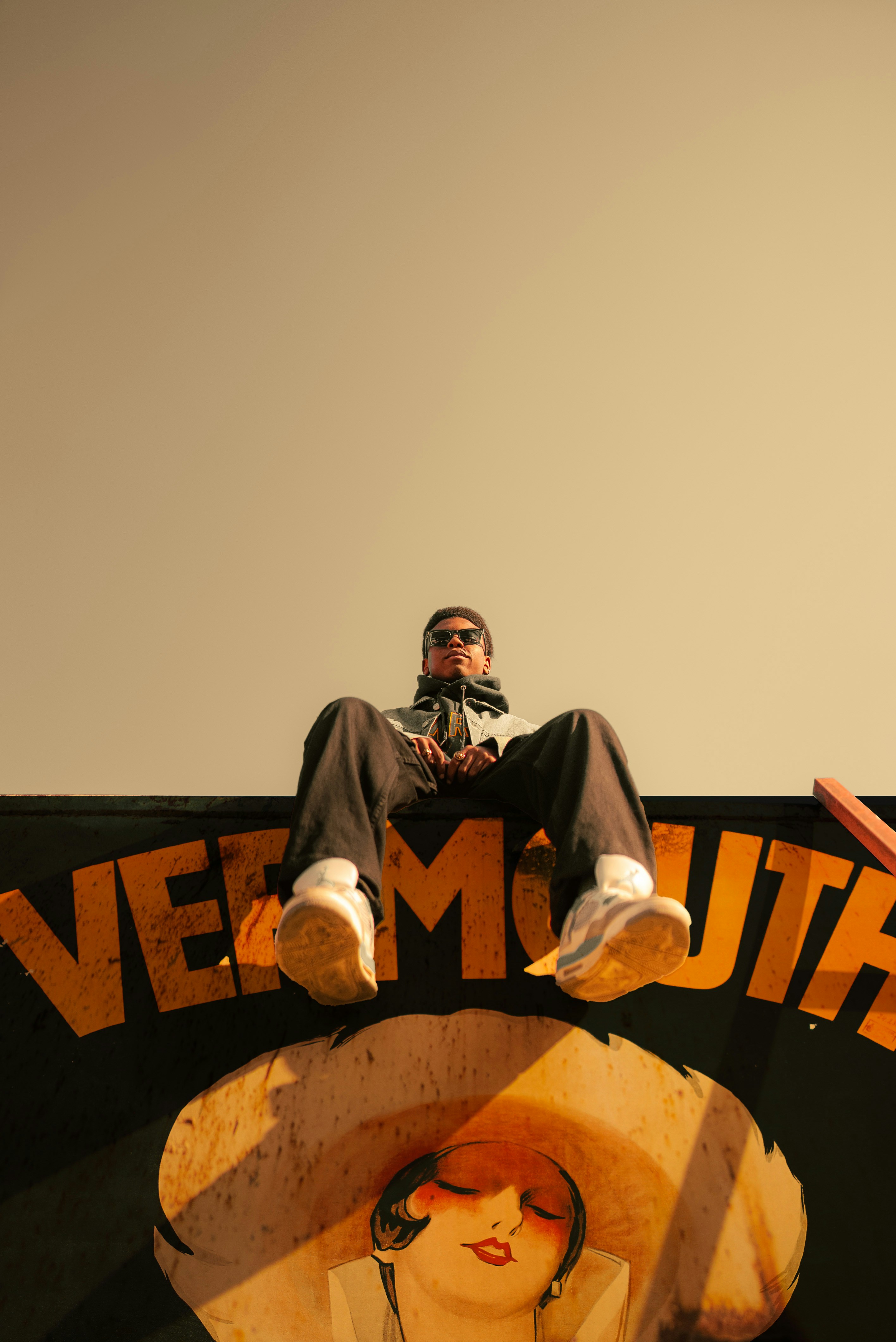 A man sitting on top of a sign next to a woman