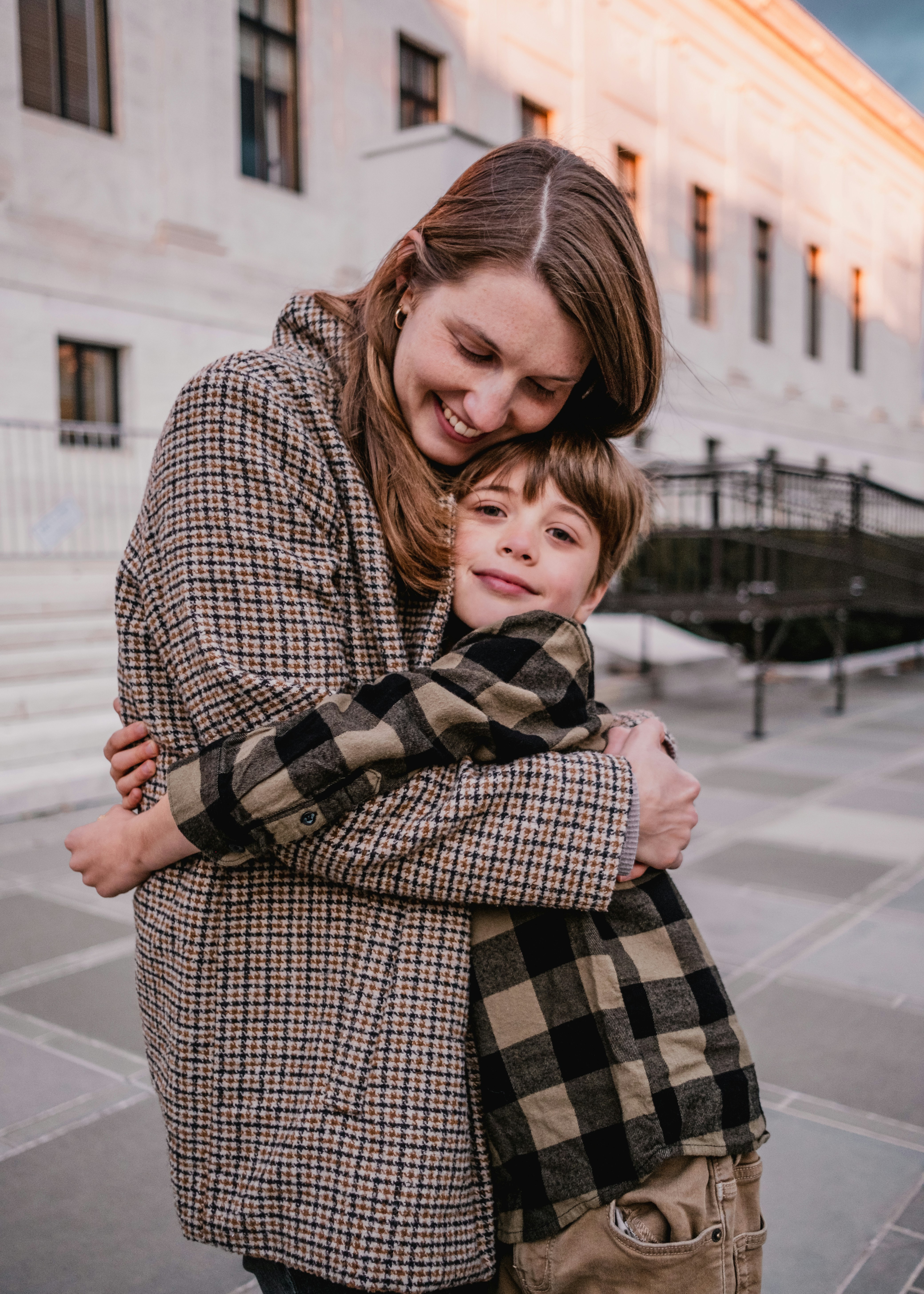 A woman hugging a young boy on the street
