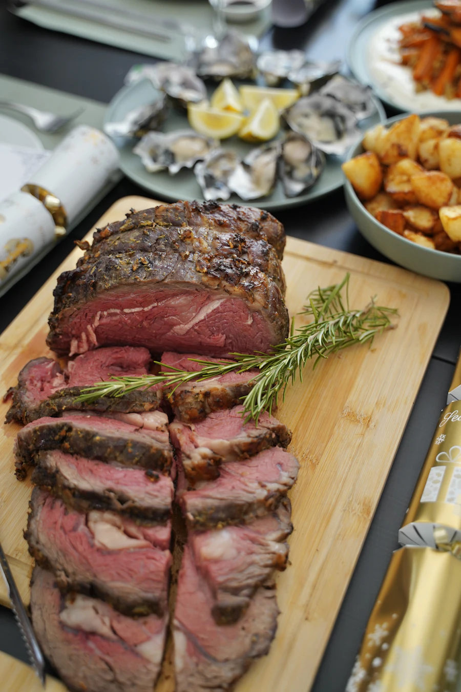 A sliced medium-rare rib roast with rosemary on a board
