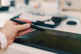 A person holding a pen and writing on a tablet