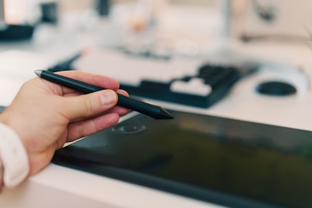 A person holding a pen and writing on a tablet