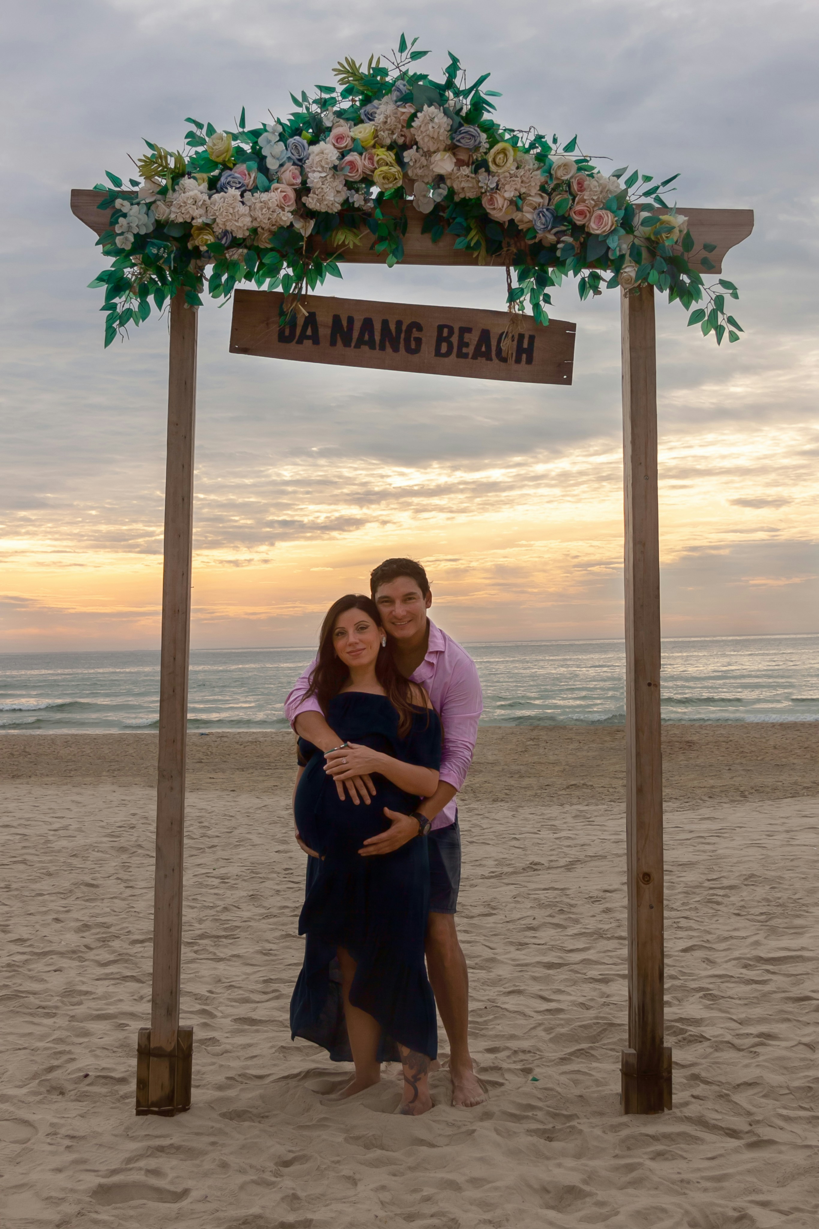 Ein Mann und eine Frau stehen unter einem Holzschild an einem Strand