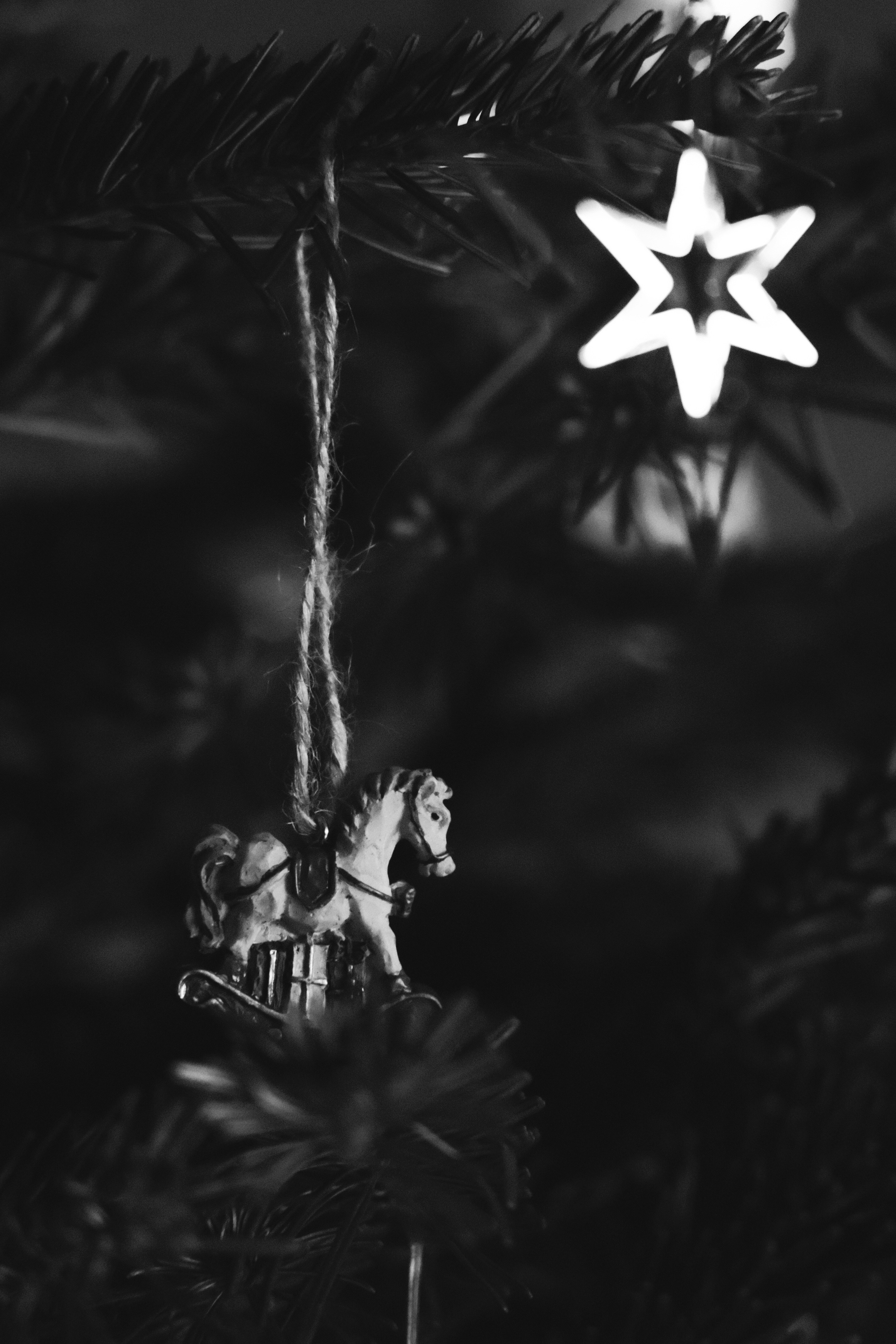 A black and white photo of a horse ornament on a christmas tree