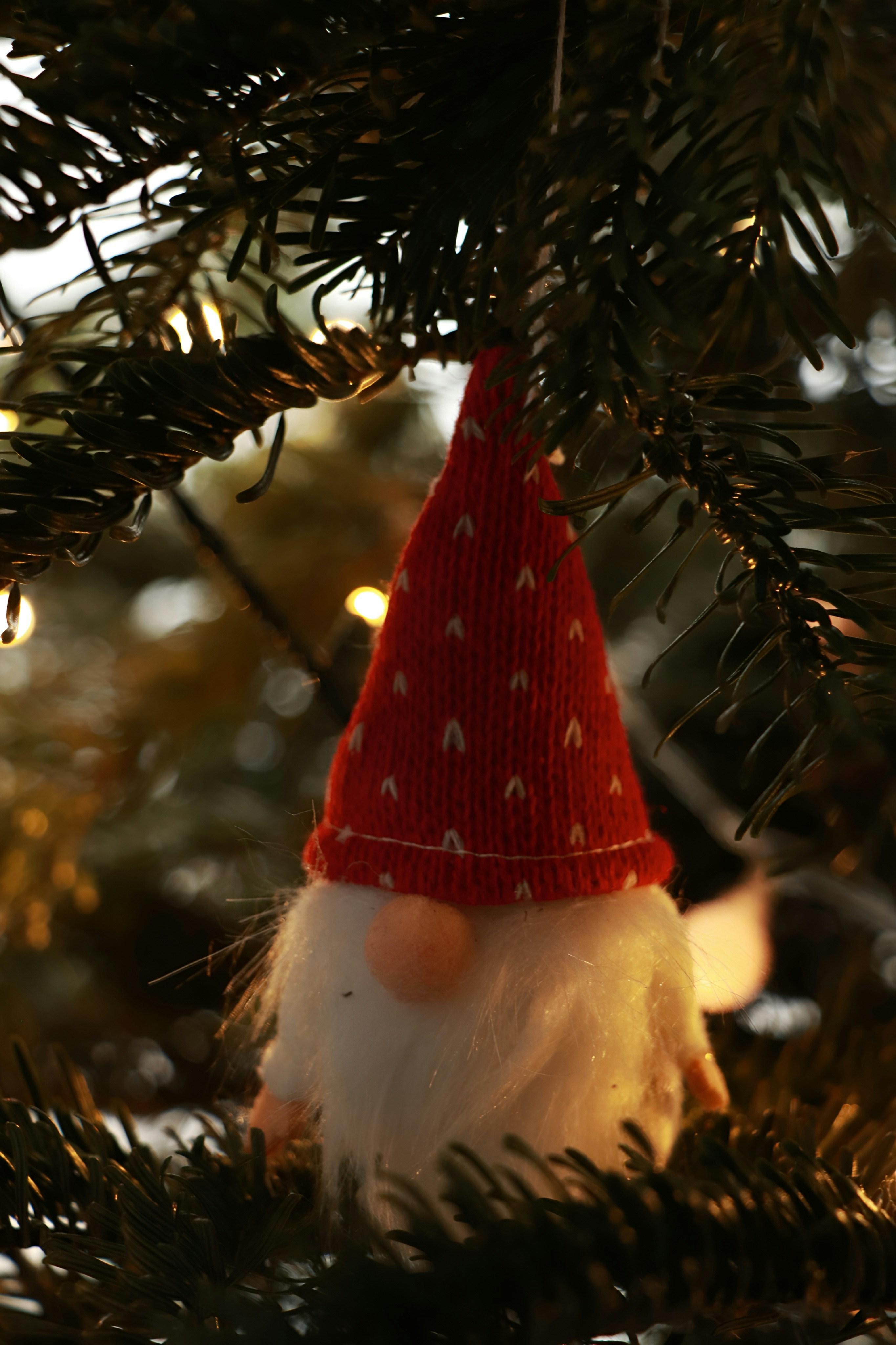 A gnome ornament hanging from a christmas tree