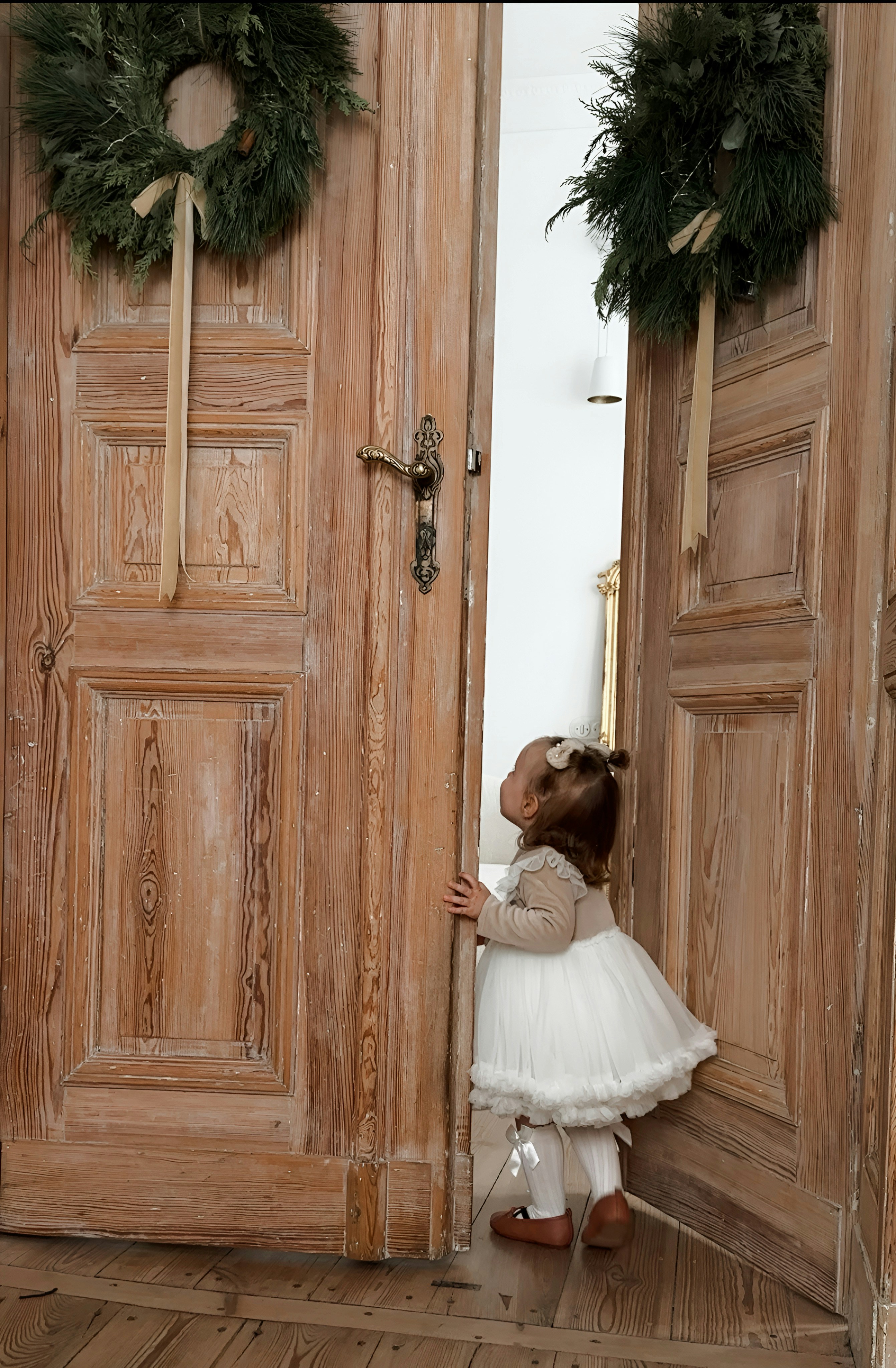 A little girl standing in front of a wooden door