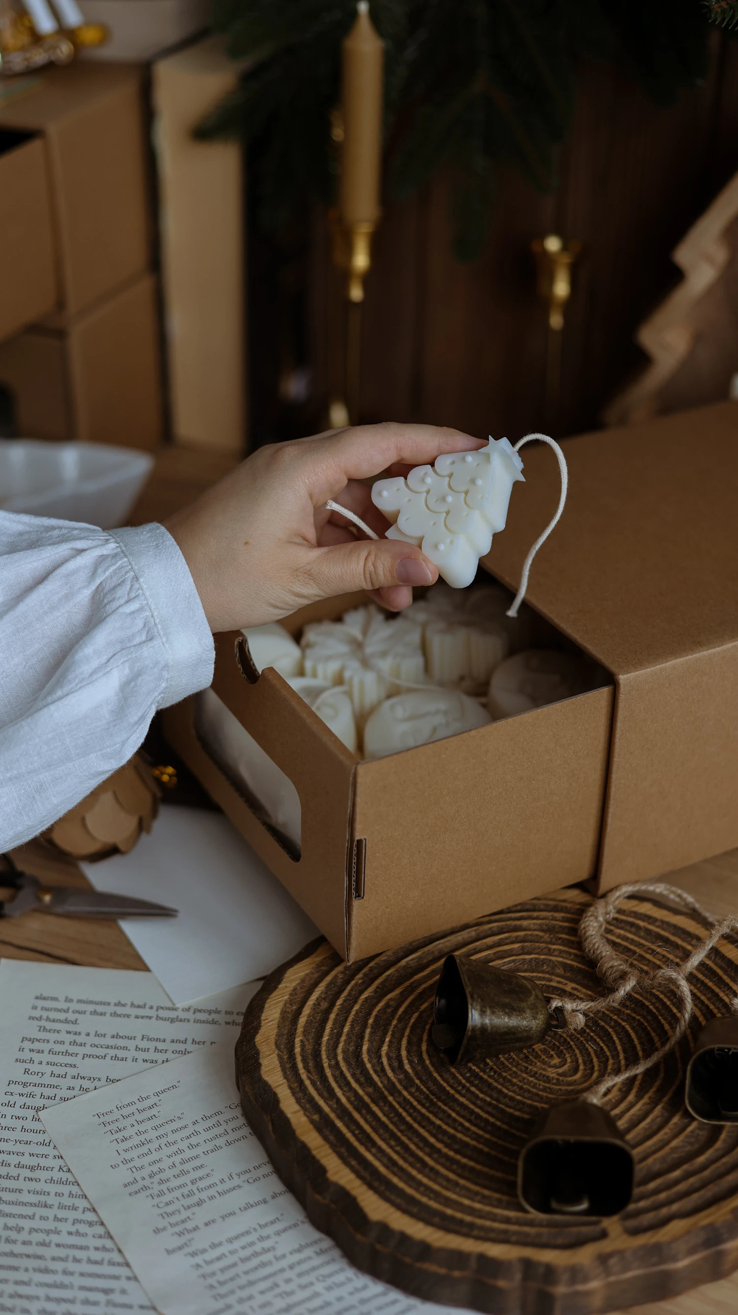 Hands packing moulded wax into a kraft box with twine and tissue beside it