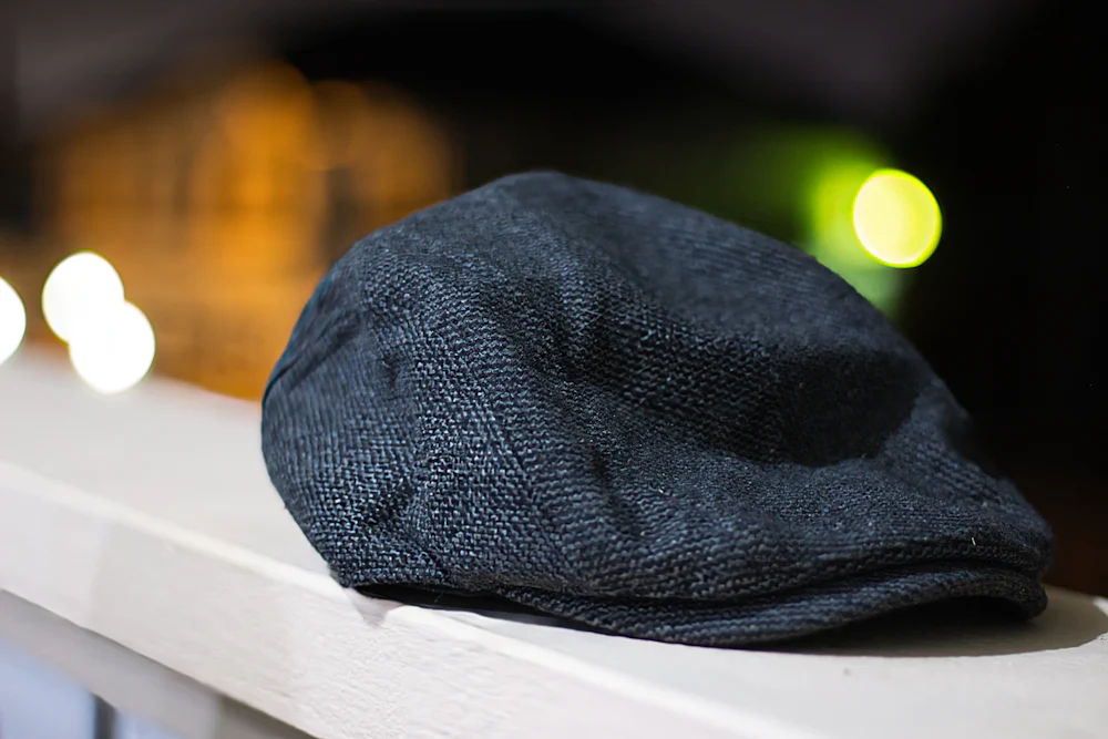 A dark wool flat cap resting on a window sill.