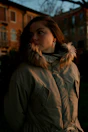 A woman in a parka standing in front of a building