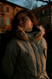 A woman in a parka standing in front of a building