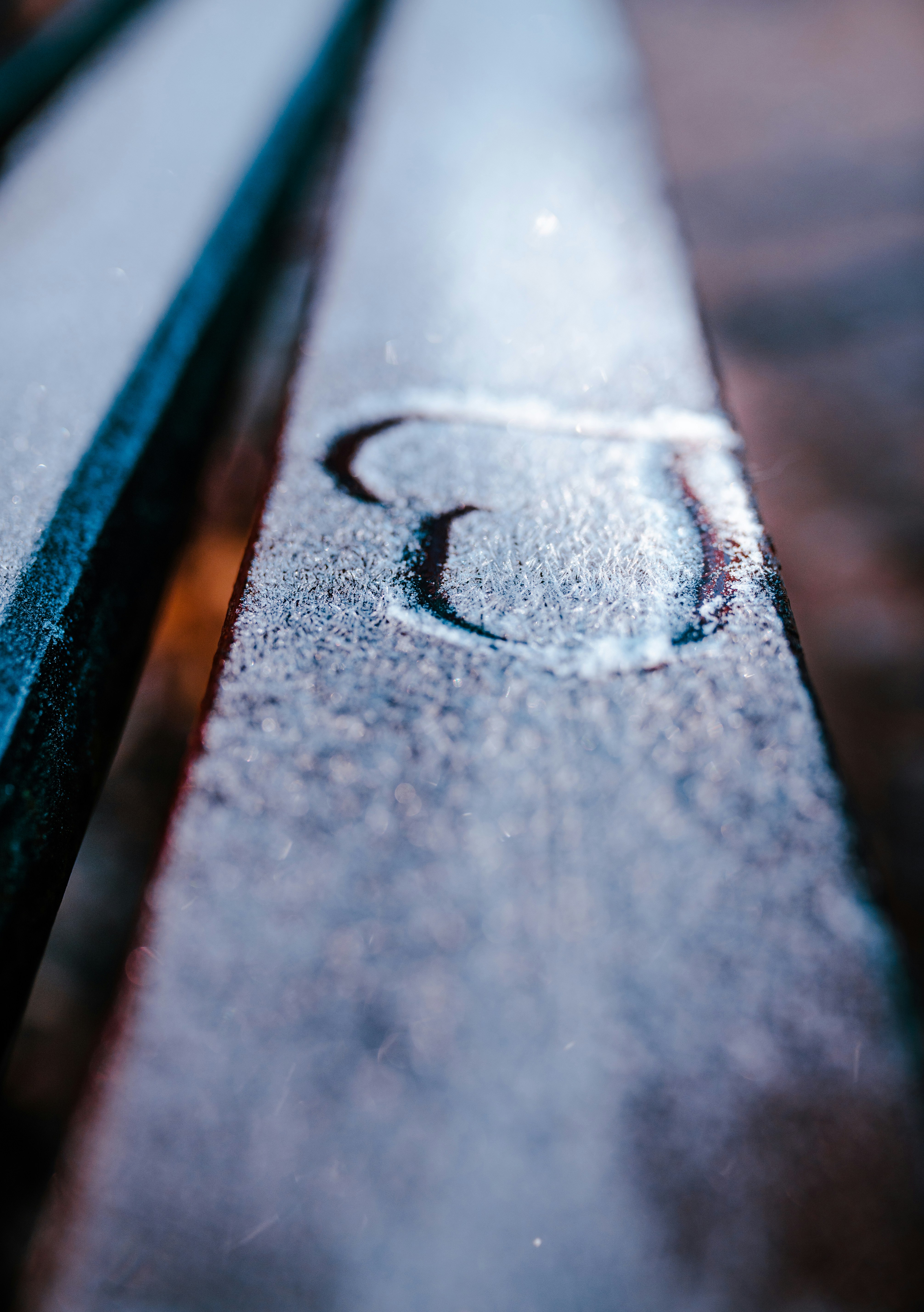 A close up of a wooden bench with snow on it