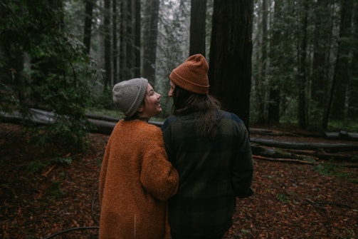 A man and a woman walking through a forest
