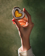 A person holding a heart shaped cookie in their hand