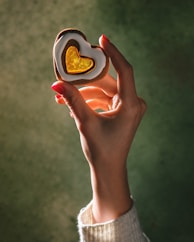 A person holding a heart shaped cookie in their hand