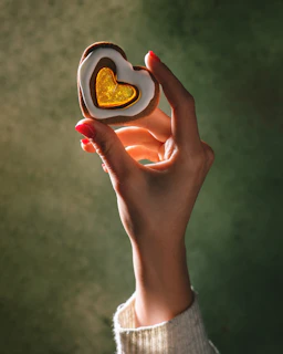 A person holding a heart shaped cookie in their hand