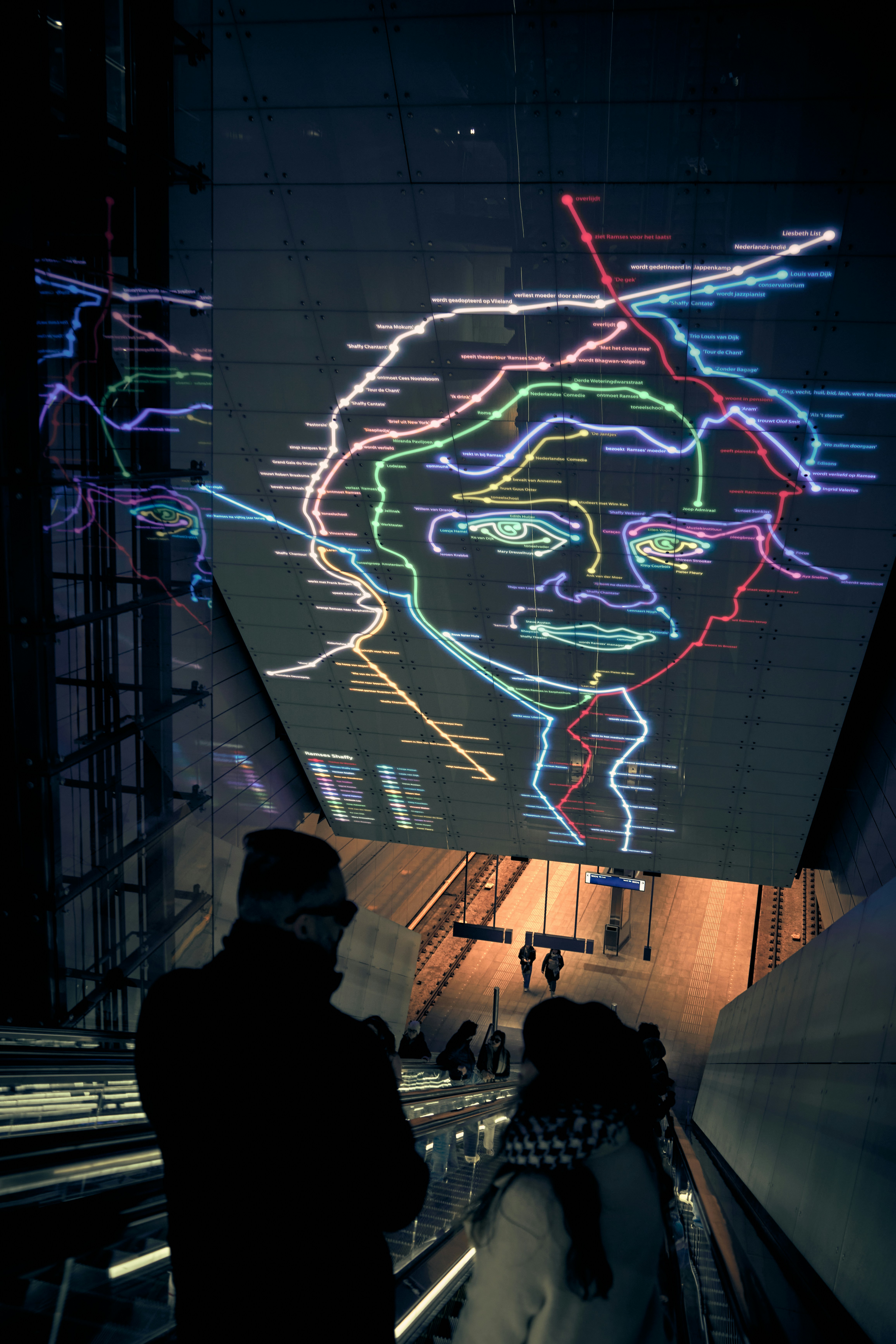 Two people walking down an escalator at night