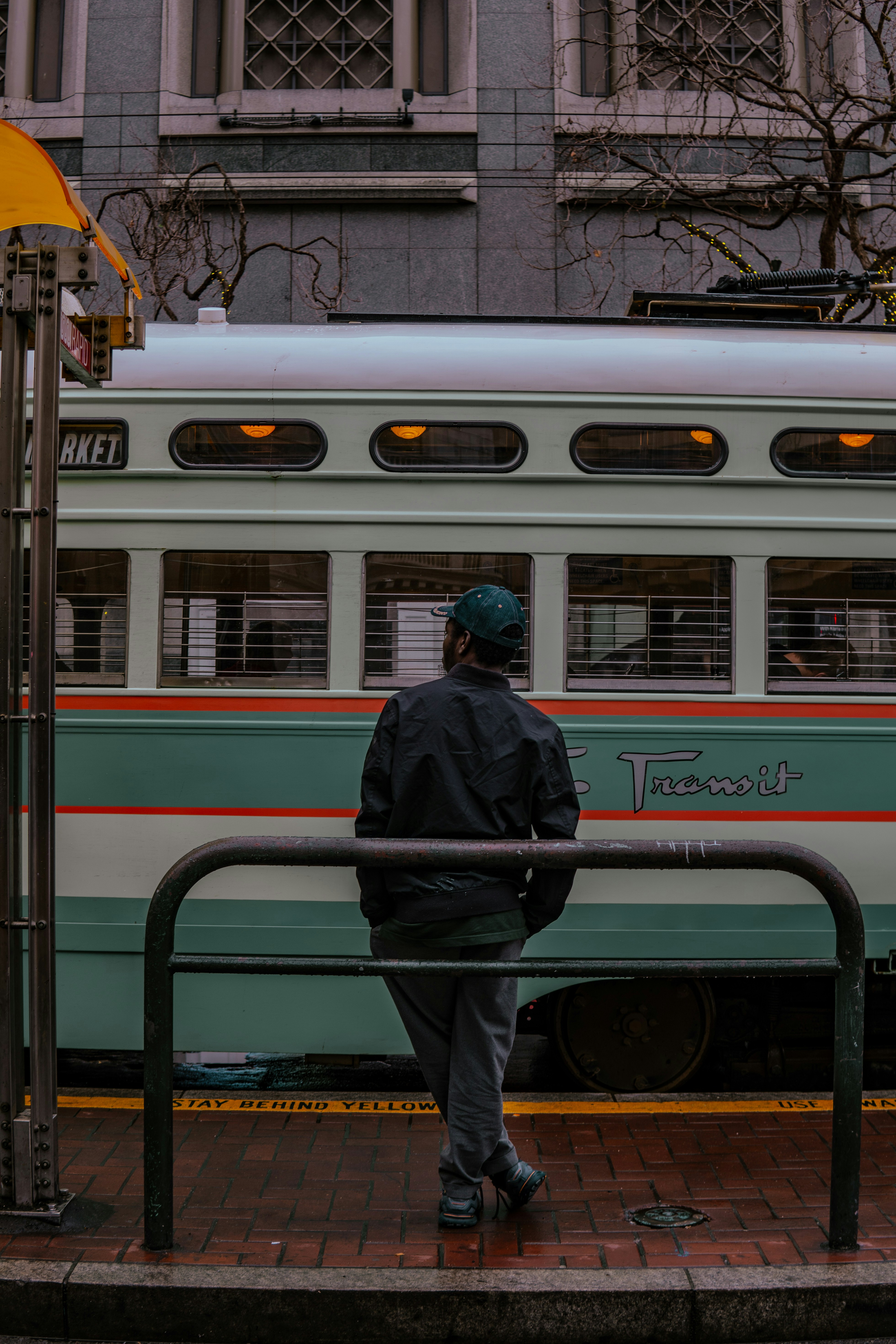 A man standing on a sidewalk next to a train