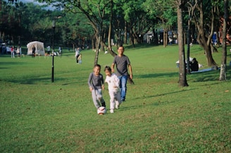A group of people walking across a lush green park