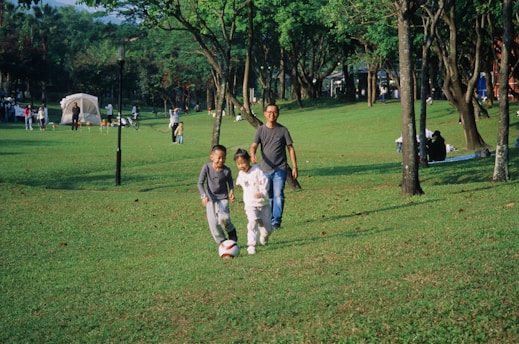 A group of people walking across a lush green park