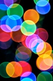 A blurry photo of colorful lights on a black background