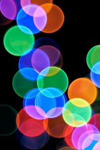 A blurry photo of colorful lights on a black background