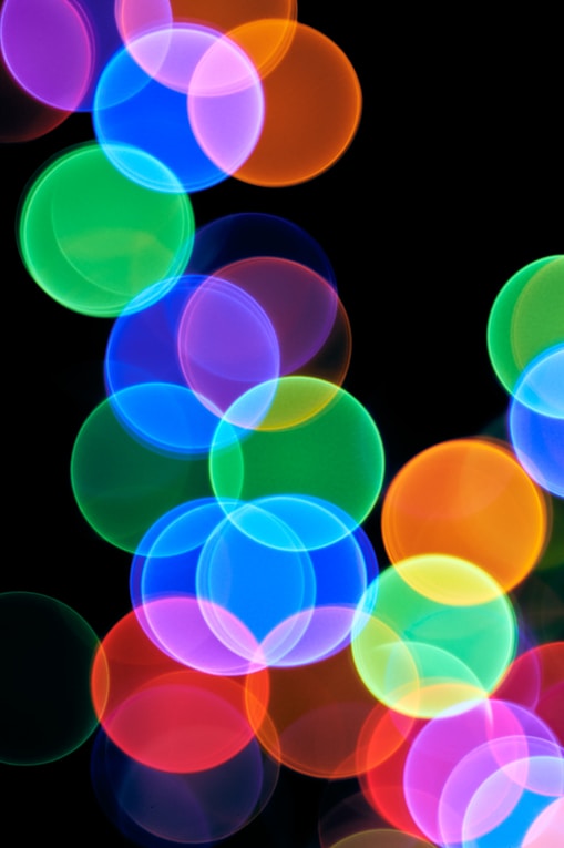 A blurry photo of colorful lights on a black background
