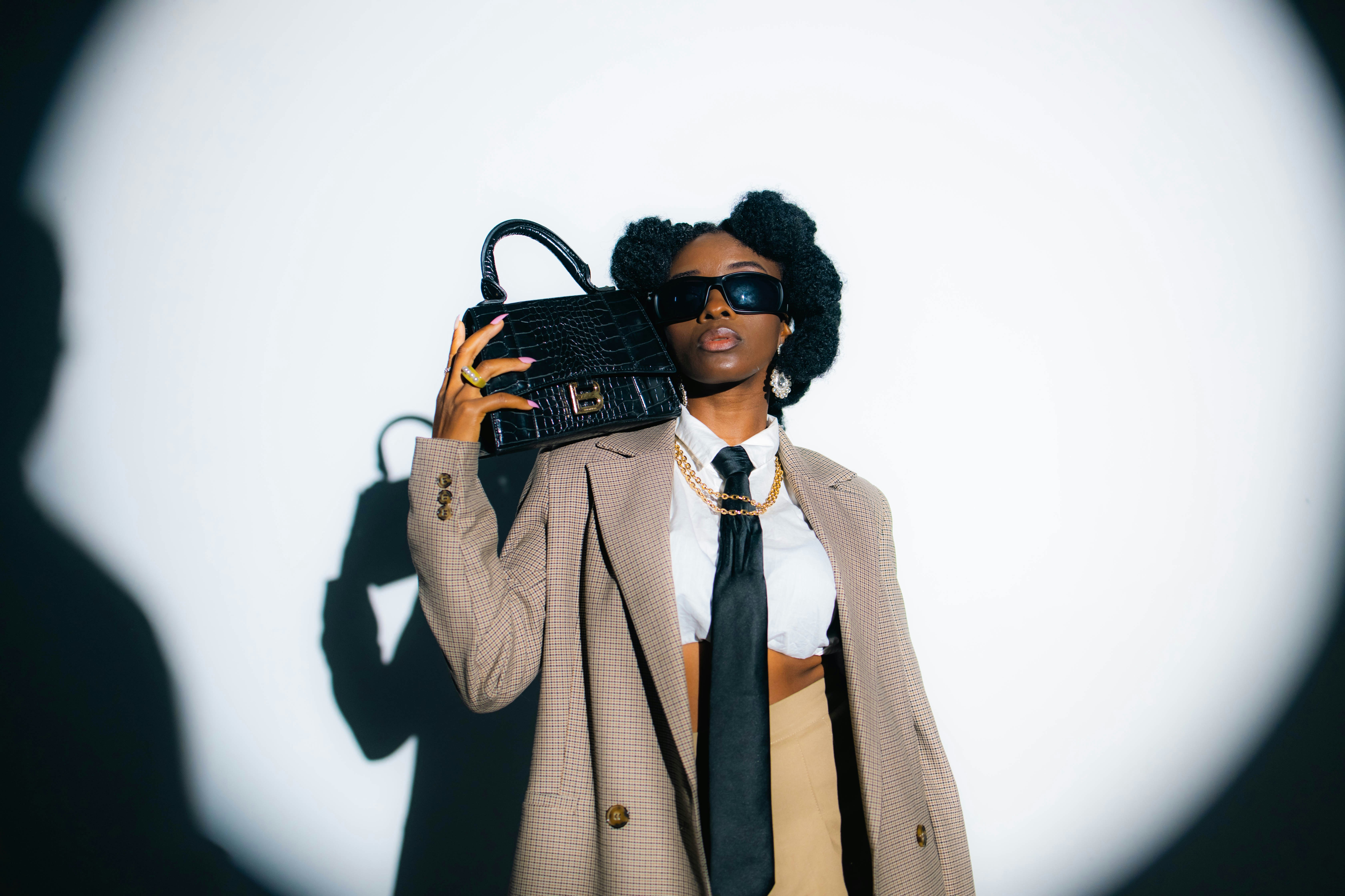A woman in a coat and tie holding a purse