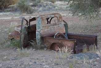 An old rusted out truck sitting in the middle of a field