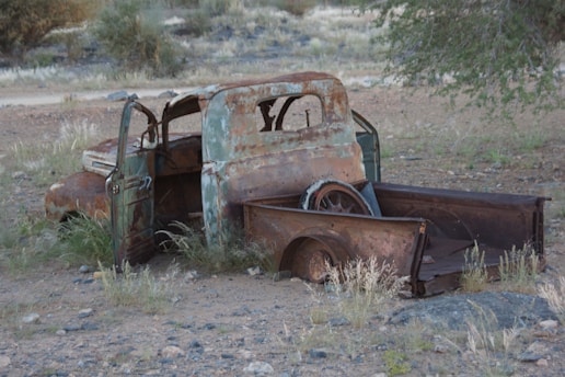 An old rusted out truck sitting in the middle of a field