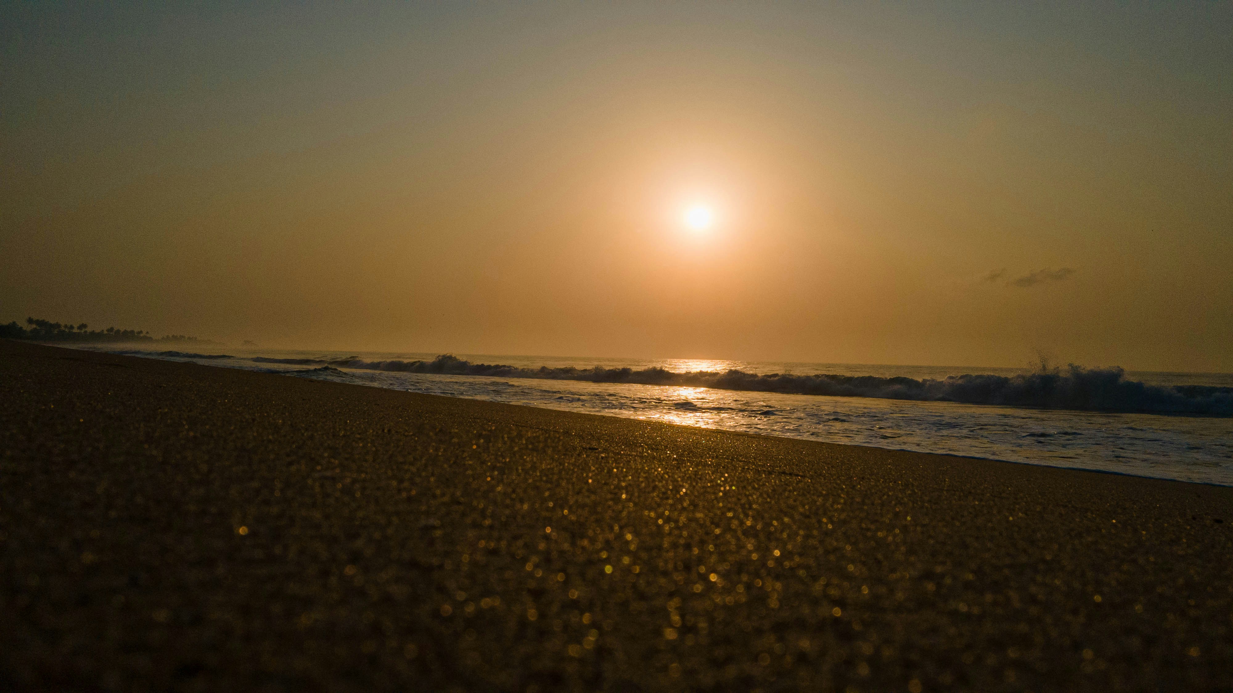The sun is setting over the ocean on the beach