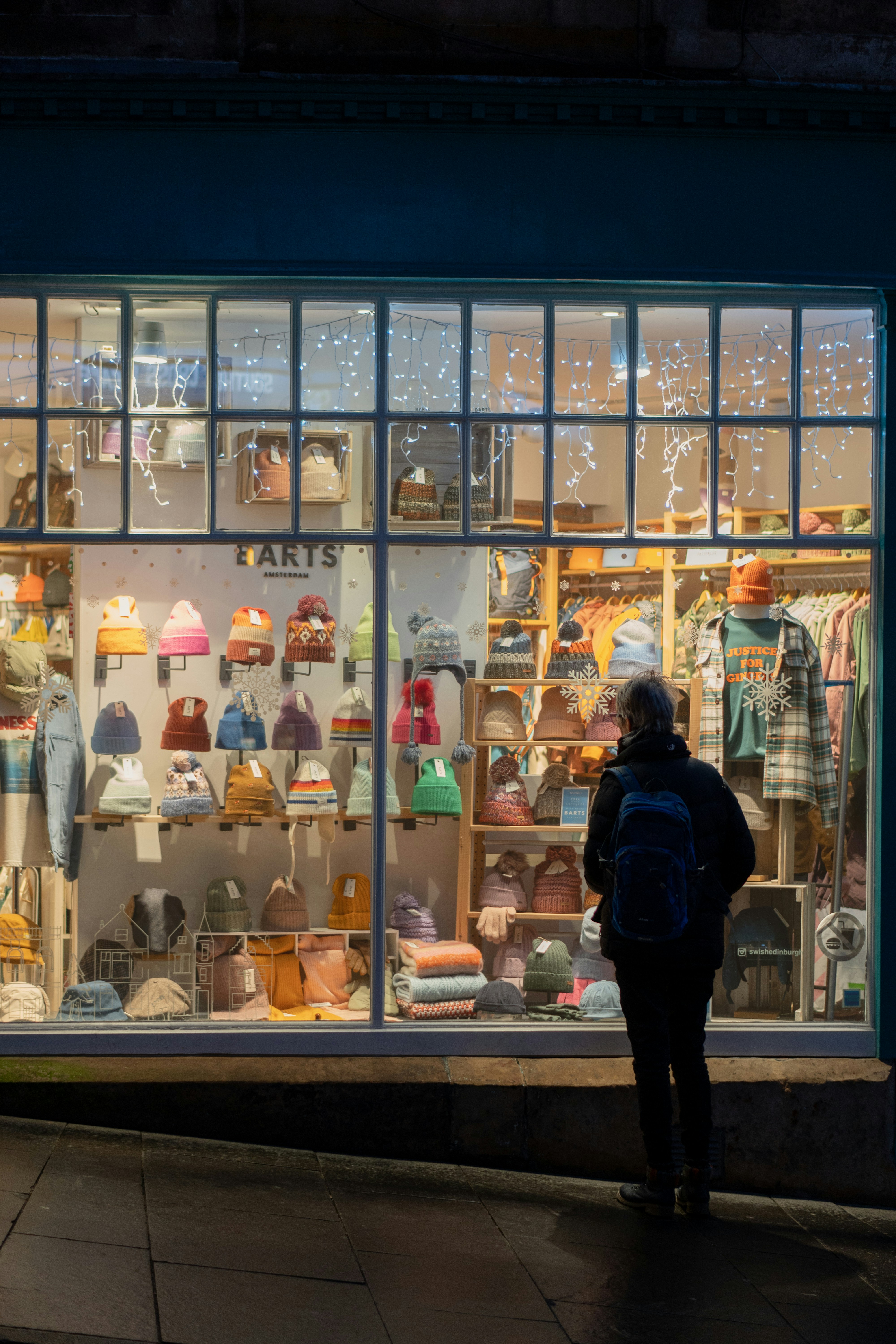 A person standing in front of a store window at night