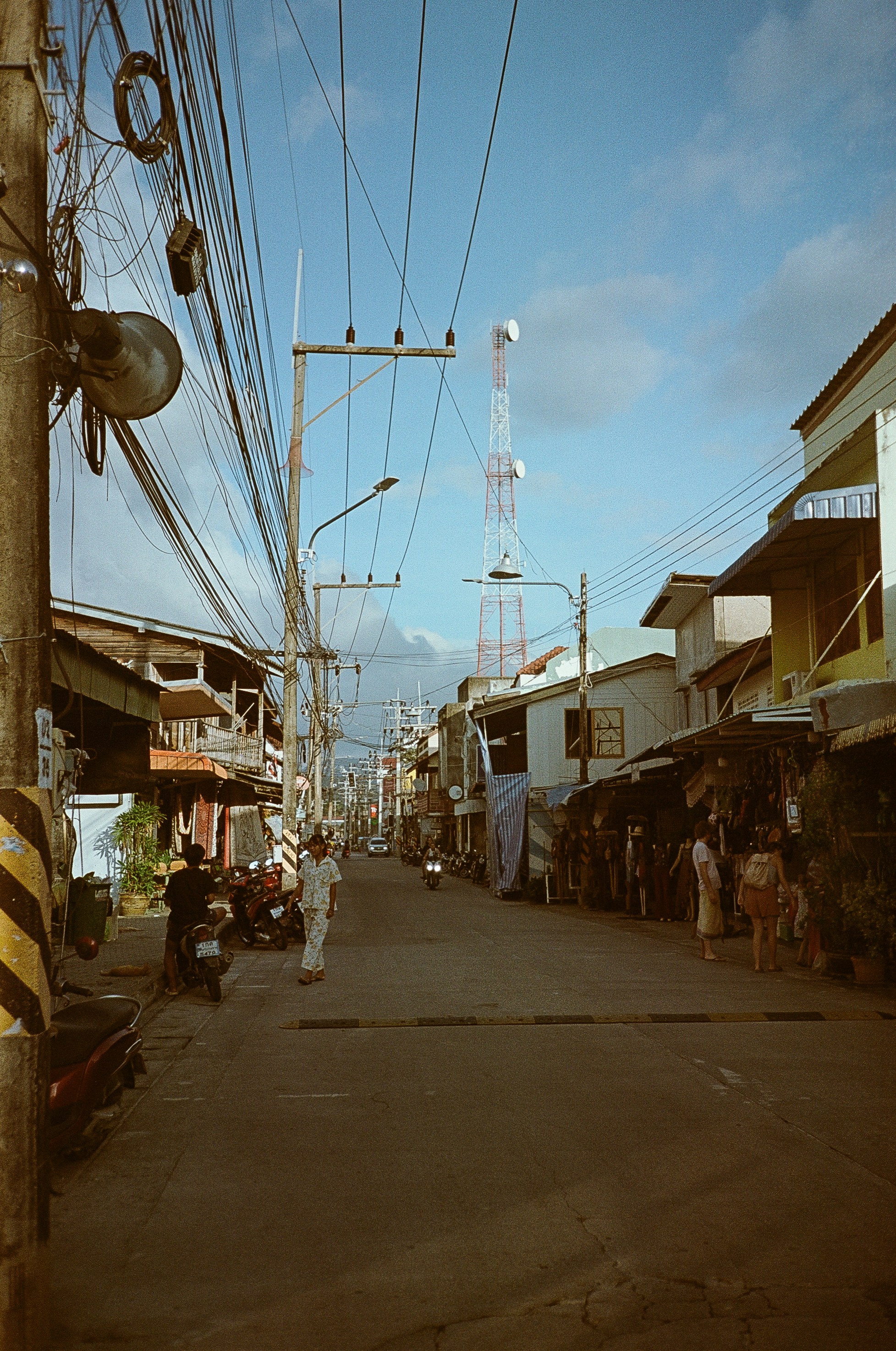 A narrow street with people standing on the side of it
