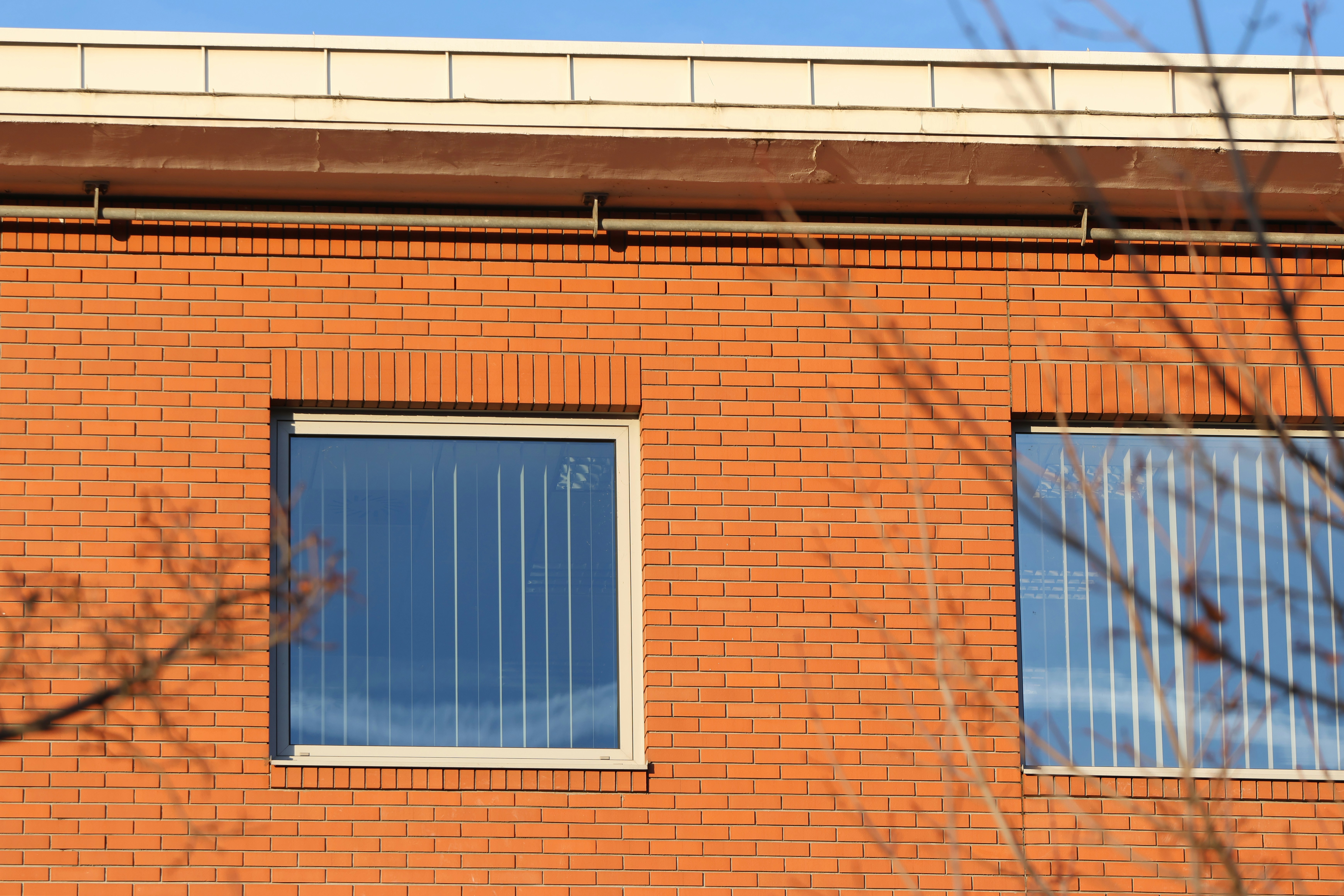 A red brick building with two windows and a white roof