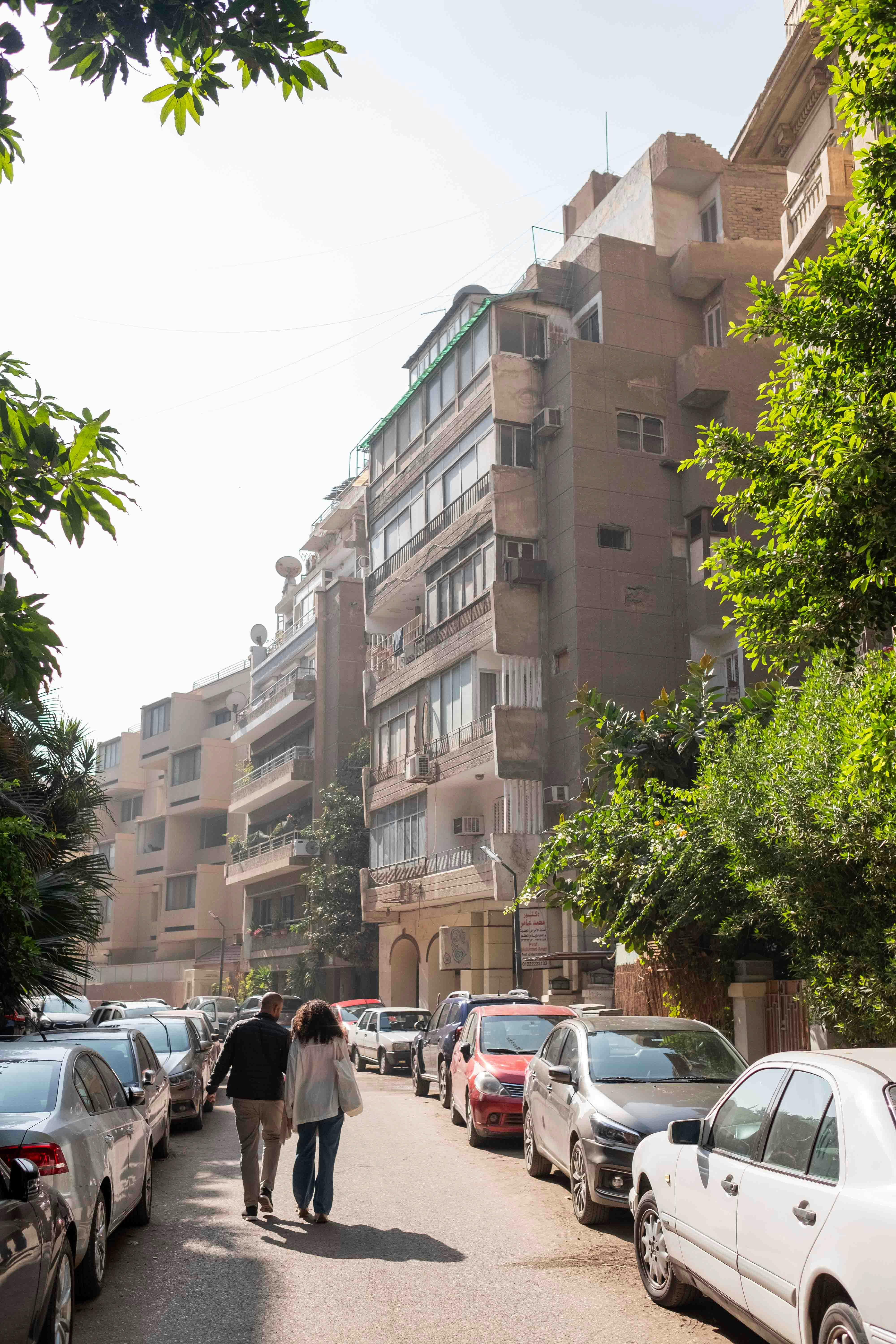 주차된 차 옆 거리를 걷고 있는 두 사람