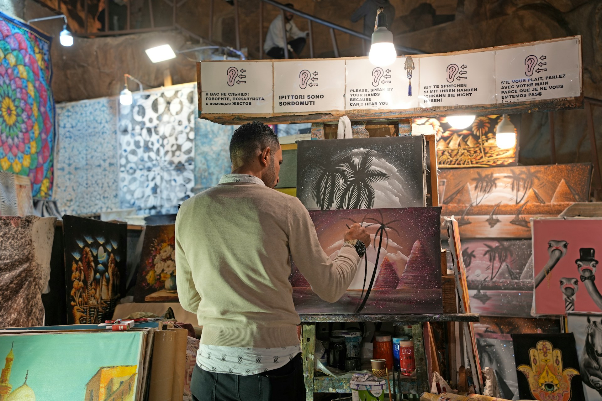A man standing in front of a display of paintings