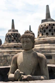 A statue of a buddha sitting in front of a row of stone buildings