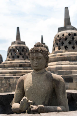 A statue of a buddha sitting in front of a row of stone buildings