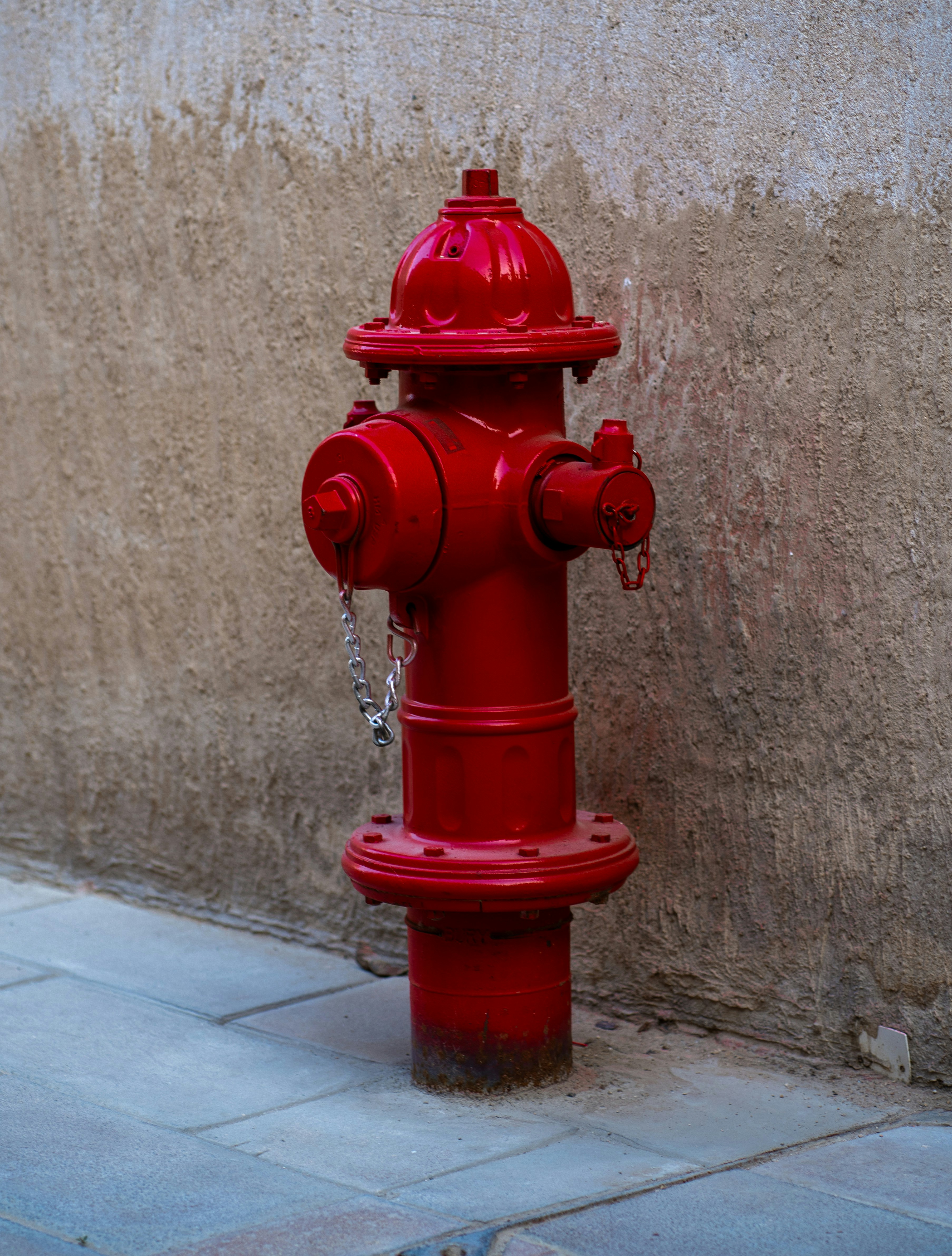 A red fire hydrant on the side of a building