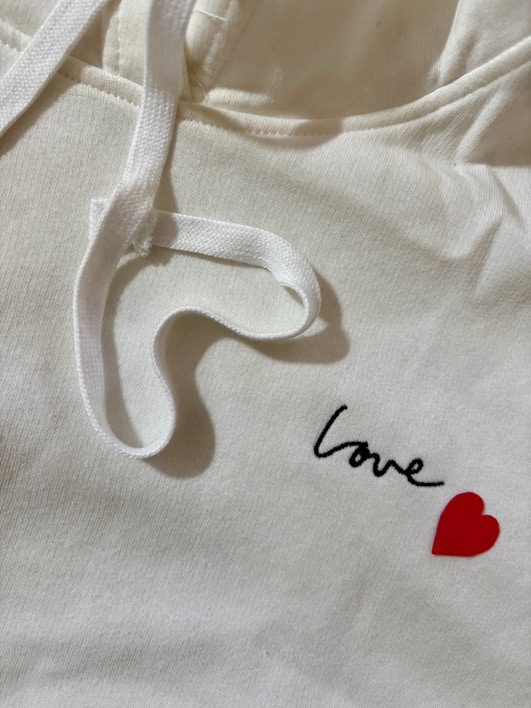 A white shirt with a red heart on it