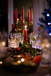 A table topped with lots of glasses next to a christmas tree