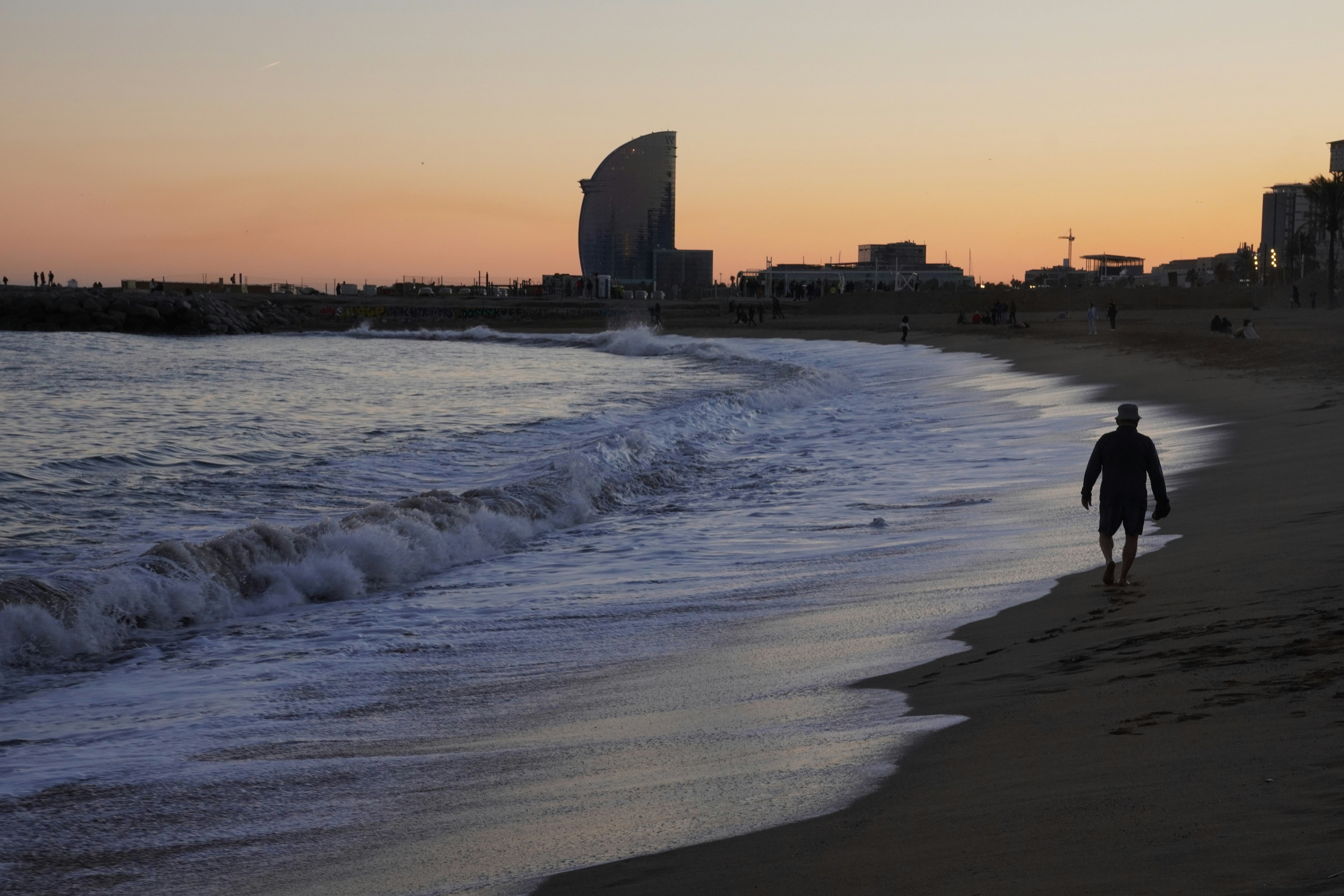 A man walking along a beach next to the ocean