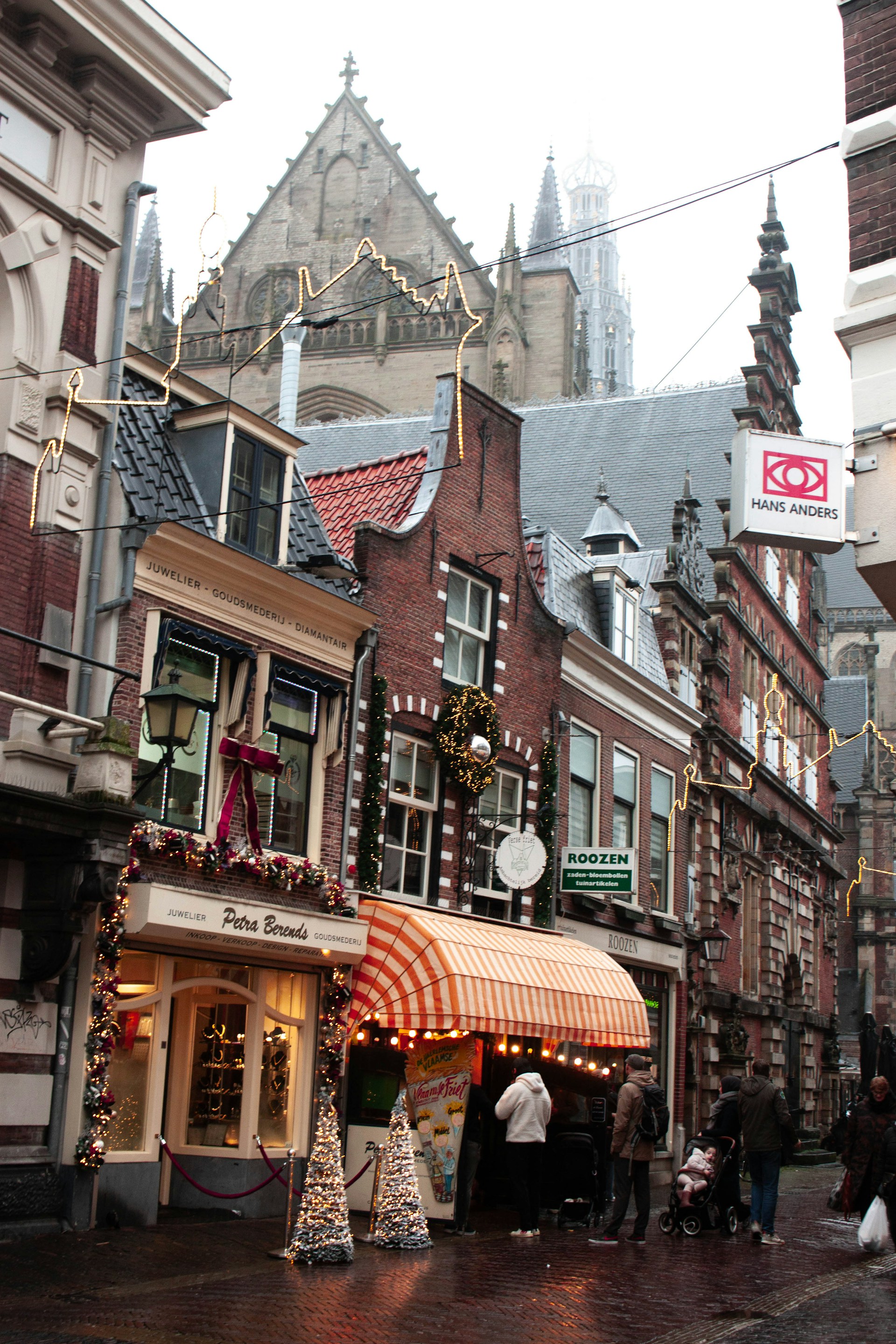 A group of people walking down a street next to tall buildings